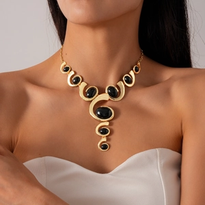 Gros plan du collier géométrique doré avec pierres ovales noires et un design épuré