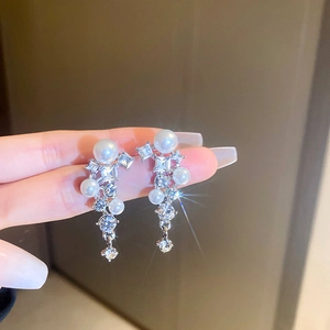 Detail of silver drop earrings with geometric tassels, pearls, and sparkling crystals