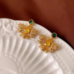 Macro shot of gold bee earrings featuring yellow zircon stones and diamond-set wings