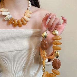 Close-up of oversized irregular acrylic beaded necklaces with gold metal accents