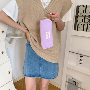 Detail view of a lavender nylon pouch with a handle held by a model in a soft setting