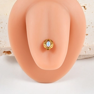 Vue macro d'un piercing ovale doré avec opale irisée sur un modèle en silicone
