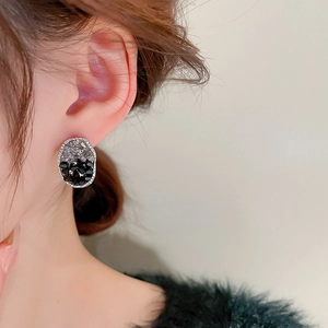 Gros plan de boucles d'oreilles ovales avec cristaux noirs et gris et bord en zircon