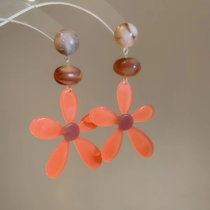 Macro shot of resin flower earrings with marble pattern beads and gold metal links