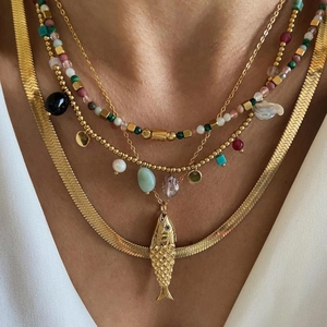 Layered gold titanium necklaces with fish pendant, pearls, and colorful beads on neck