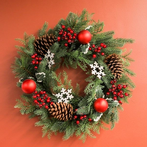 Christmas wreath with pine cones red berries and snow flakes on an orange background