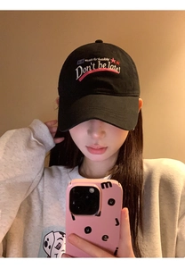 Detailed close-up of embroidered Don't be late text and red stars on black baseball cap