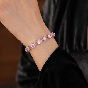 Close-up of sparkling pink round zircon tennis bracelet on black velvet background