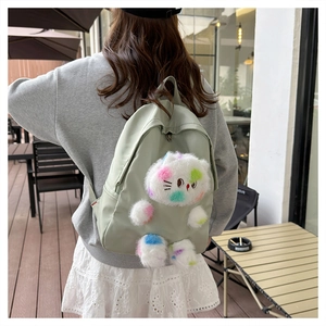Foto all'aperto di uno zaino in nylon verde chiaro con un simpatico gatto di peluche