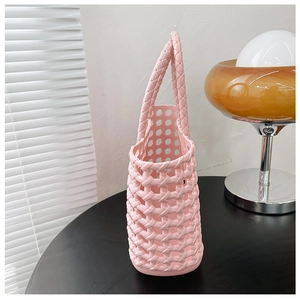 Close-up of pink woven jelly basket bag featuring hollow grid texture and durable handle