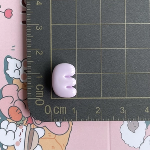 Detailed scale view of a small purple resin letter E charm on a measurement grid mat