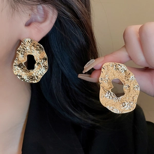 Detailed close-up of chunky gold hoop earrings with irregular hammered metal texture