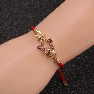 Détail du bracelet tressé rouge avec pendentif étoile dorée et zircons violets et blancs