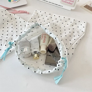 Polka dot drawstring bags showing storage capacity for cosmetics on white surface