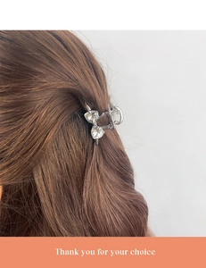 Detail of silver hair claw clip with heart-shaped rhinestones worn on brown hair