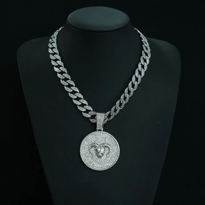 Macro detail of Aries zodiac pendant with crystal paving and silver Cuban chain link
