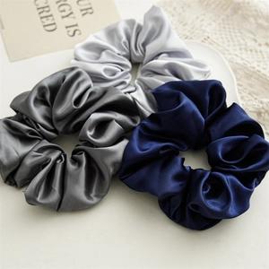 Detailed texture of glossy satin scrunchies in navy, dark gray and silver set