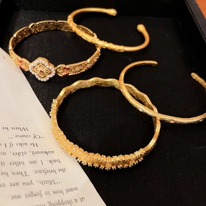 Close-up of gold clover bracelet set with pearls and rubies on black background