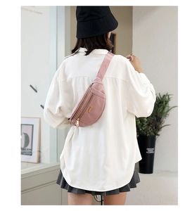 Pink nylon fanny pack worn as a crossbody chest bag with adjustable strap and zipper