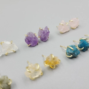 Close-up of four-claw set amethyst and rose quartz studs with golden finish