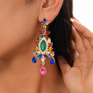Close-up of vintage drop earrings with colorful crystals and stones on a model