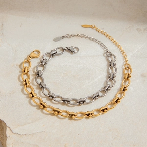 Industrielle Edelstahl-Kettenarmbänder in Gold und Silber auf Stein-Hintergrund