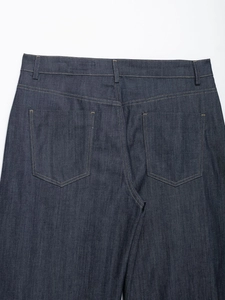 Dettaglio dei jeans a botte a vita alta con cuciture gialle e tasche posteriori