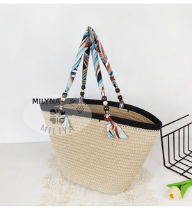 Detail of straw woven tote with silk scarf wrapped handles and decorative wood beads