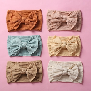 Juego de seis diademas de nailon jacquard para bebé con lazos grandes en colores.