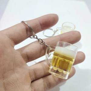 Miniature beer mug keychain with realistic liquid and foam held in hand