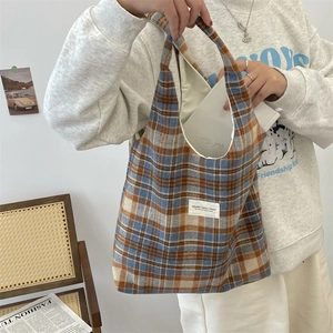 Macro detail of plaid wool tote bag showing texture and white woven brand label