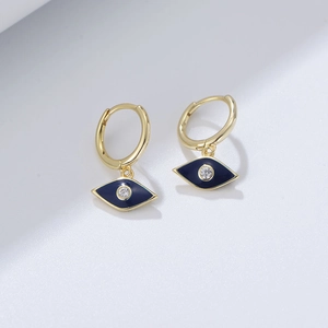 Macro shot of gold Evil Eye drop earrings with blue enamel and sparkling zircon