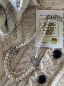 Détail d'un collier de perles double épaisseur avec nœuds en strass et fermoir argenté