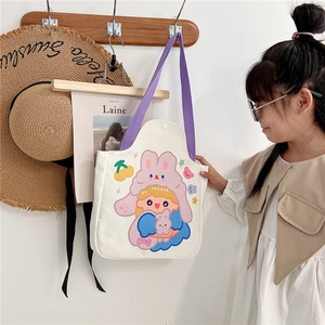 Close-up of a white canvas tote bag with cartoon girl and purple straps for kids