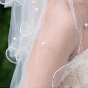 Close-up of fine white bridal mesh veil with pearl beads and intricate lace embroidery