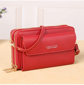 Detail view of red lychee grain leather crossbody bag showing double gold zippers and strap
