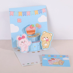 Detail view of 3D pop-up birthday card with cute bears and cake on a clean blue background