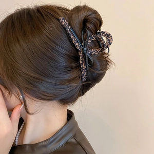 Detail of leopard print faux leather bow hair claw clip worn on a French twist hairstyle