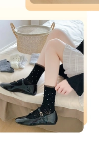 Close-up of bamboo fiber polka dot socks with lace trim and patent Mary Jane shoes