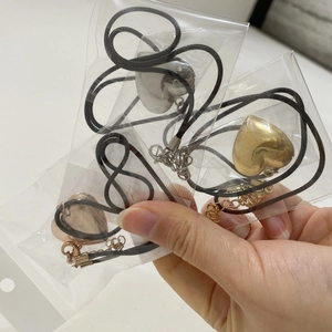Detailed view of heart locket pendants in gold, silver, and rose gold on black cords