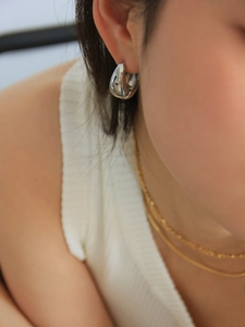 Polished silver teardrop hoop earrings and gold layered necklace on model detail