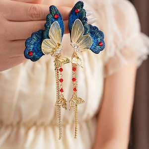 Detailaufnahme von Vintage-Schmetterlingsohrringen mit blauer Stickerei und Kristallen