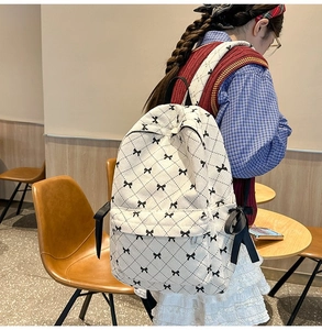 Corduroy cream backpack with black bow pattern and diamond quilting on girl's back
