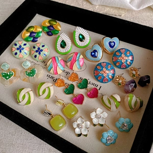 Detailed close-up of colorful enamel heart and floral stud earrings set in vintage style