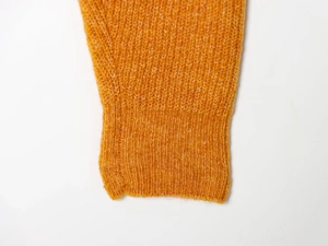 Detailed macro view of orange knit sweater showing fine ribbed cuffs and wool texture