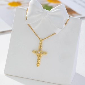 Detail of gold-plated cross necklace with zircons on a white bow jewelry stand