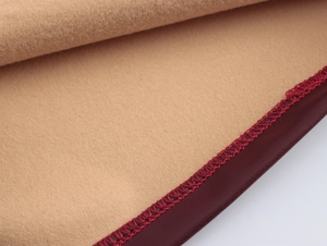 Detail of camel felt fabric texture with deep red stitched edges on a chic vest