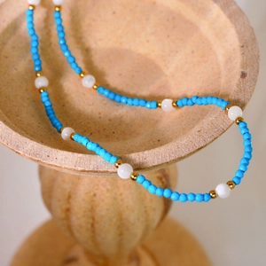 Handmade beaded necklace with blue natural stones, pearls and gold spacers on stone base