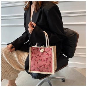 Floral canvas handbag detail with rose pattern, wood button and rope handle texture
