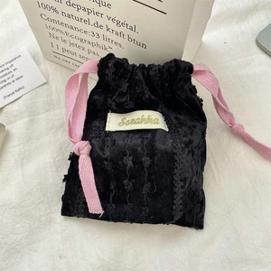 Dettaglio di sacchetto in velluto nero con coulisse rosa ed etichetta tessuta